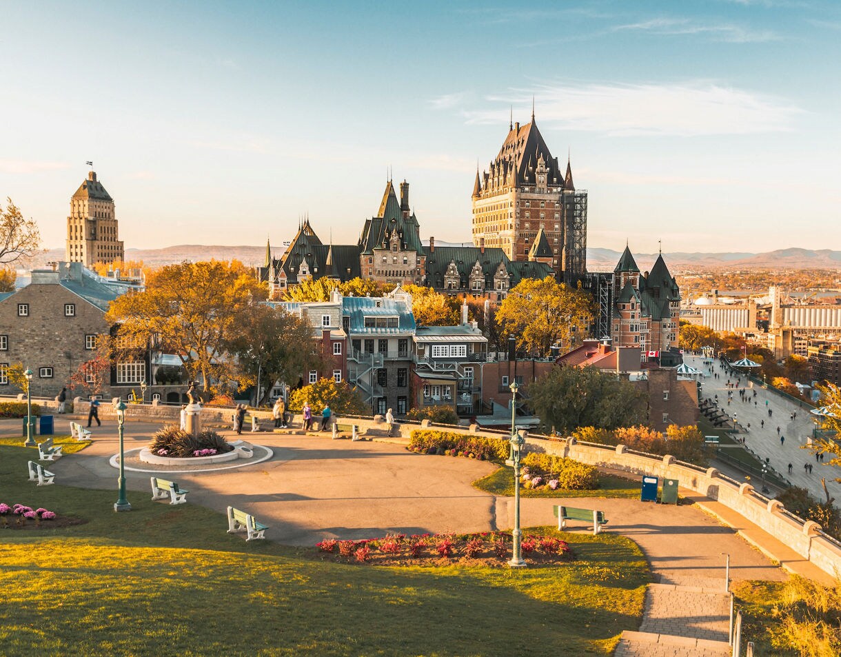 Snow-covered Dufferin Terrace with people strolling near Château Frontenac on a clear winter day.