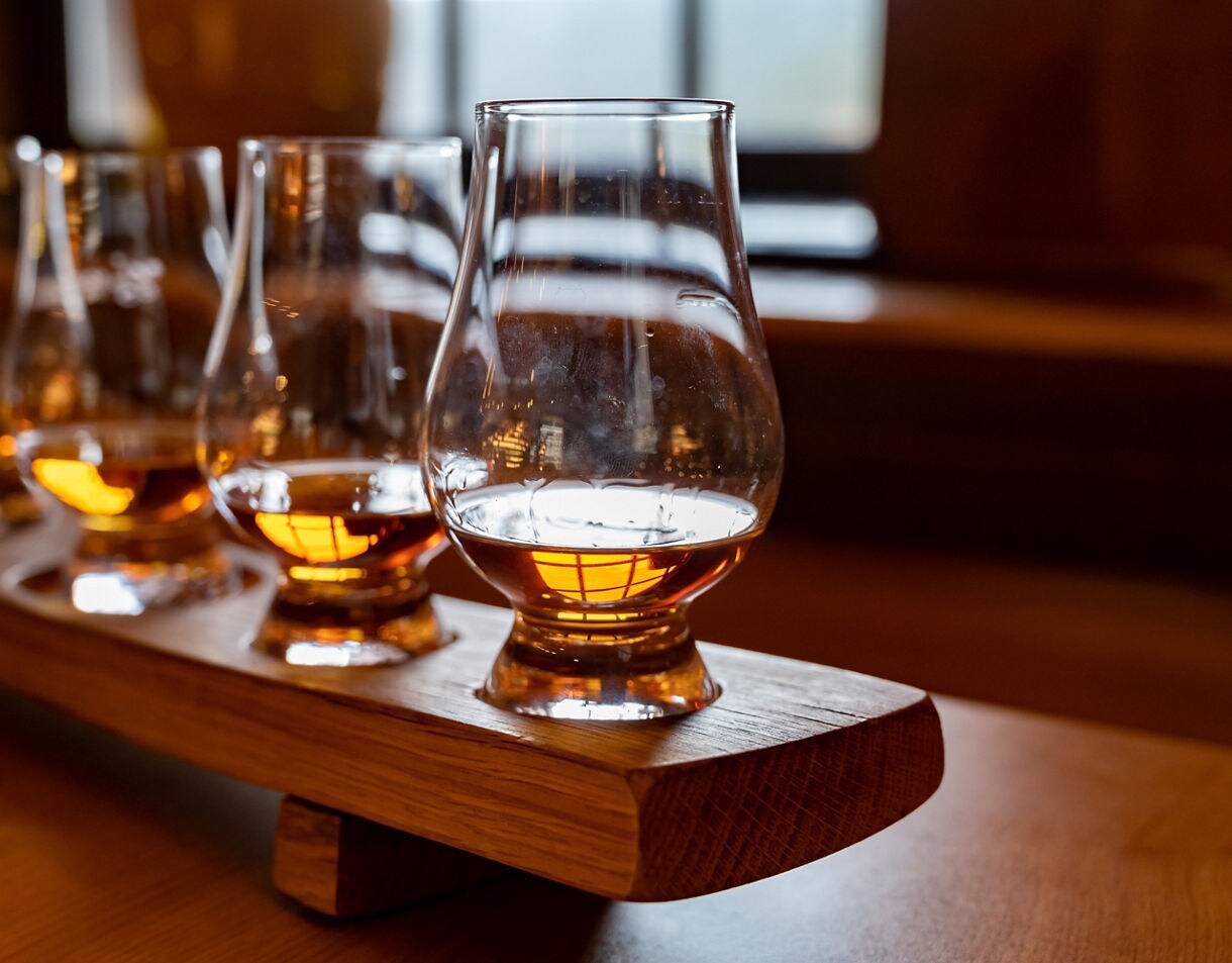 Close-up of whisky glasses filled with golden amber spirit arranged on a wooden tray.