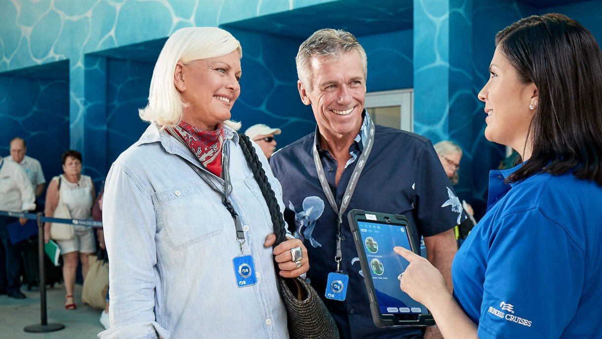 Embarkation couple smiling crew checking in medallion.