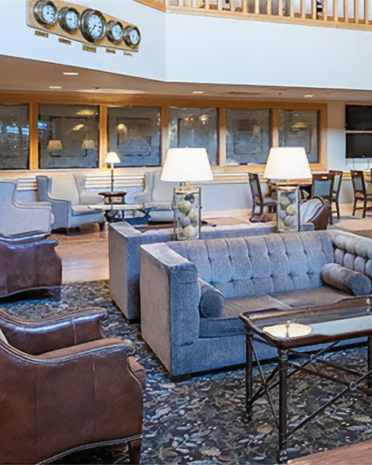  Lodge common room with blue sofa, brown leather chairs, patterned rug, and dining area visible in background.