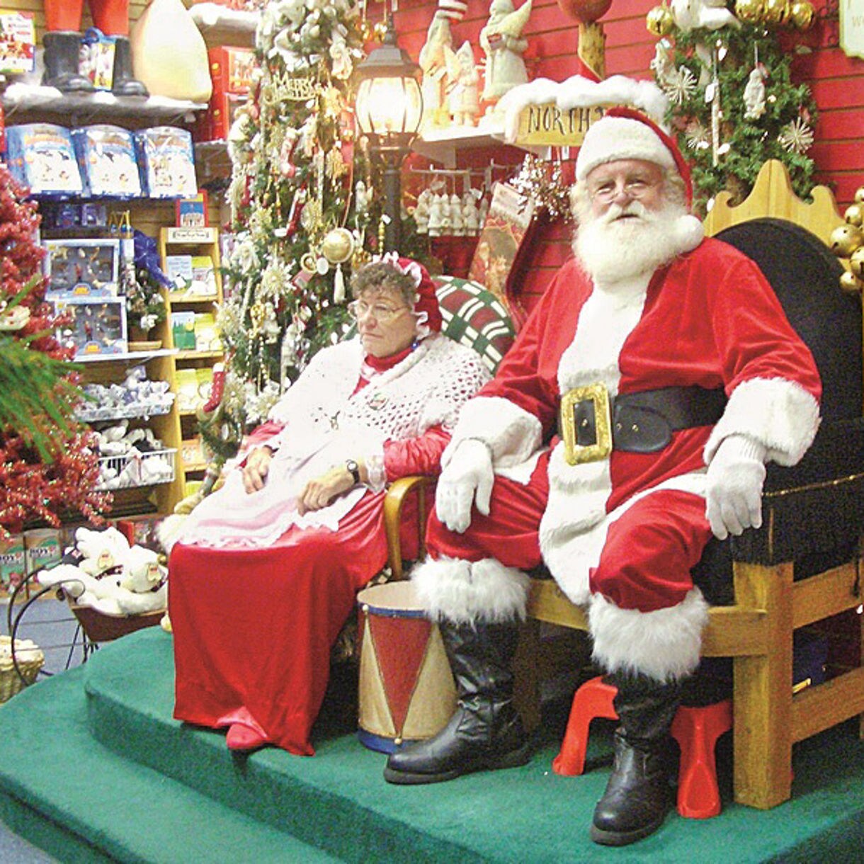 Santa Claus House in North Pole, Alaska, lit up at dusk with a towering Christmas tree in front, surrounded by snow and festive decorations on the building’s chalet-style exterior.