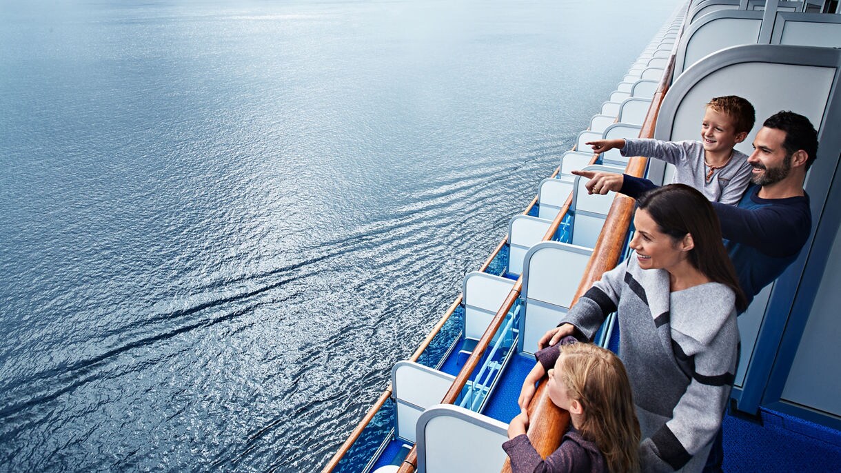 Family on stateroom balcony looking out at ocean