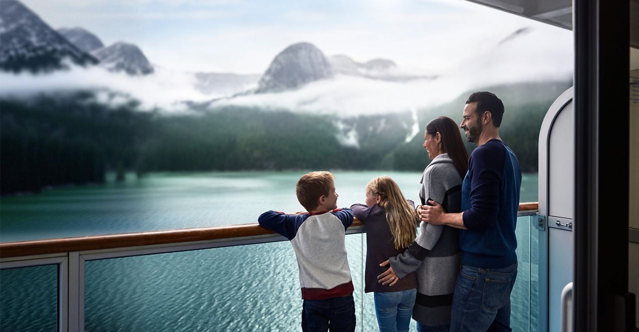 Family viewing Alaska scenery from cruise stateroom balcony