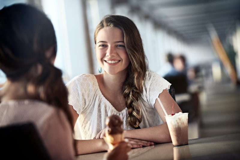 Girls enjoying gelato in café setting.