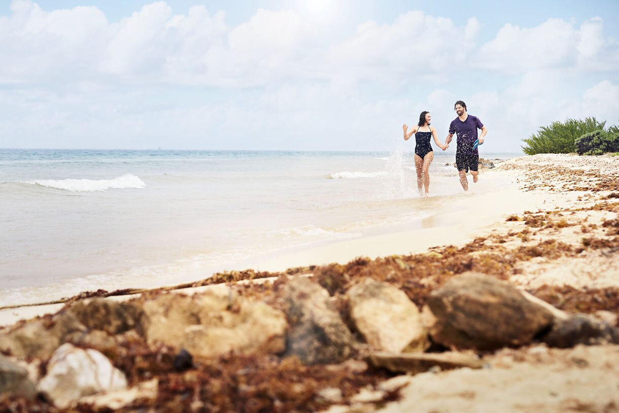 A couple running on a beach in Grand Cayman.