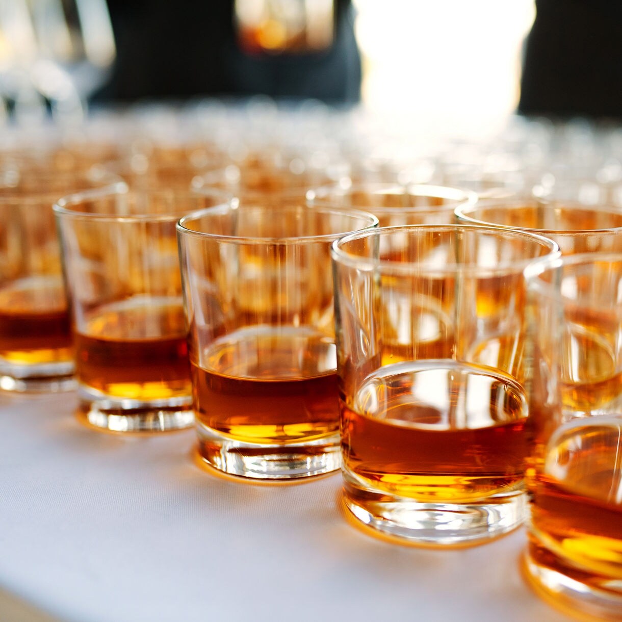 Glasses filled with golden Cayman rum arranged on a wooden table with warm lighting in the background.