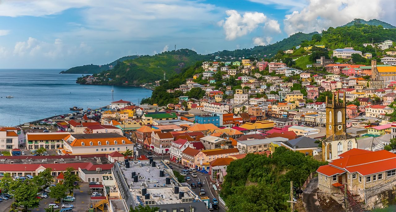 Elevated view of St. George’s, Grenada, showing colorful hillside buildings, a historic church and the bay in the distance