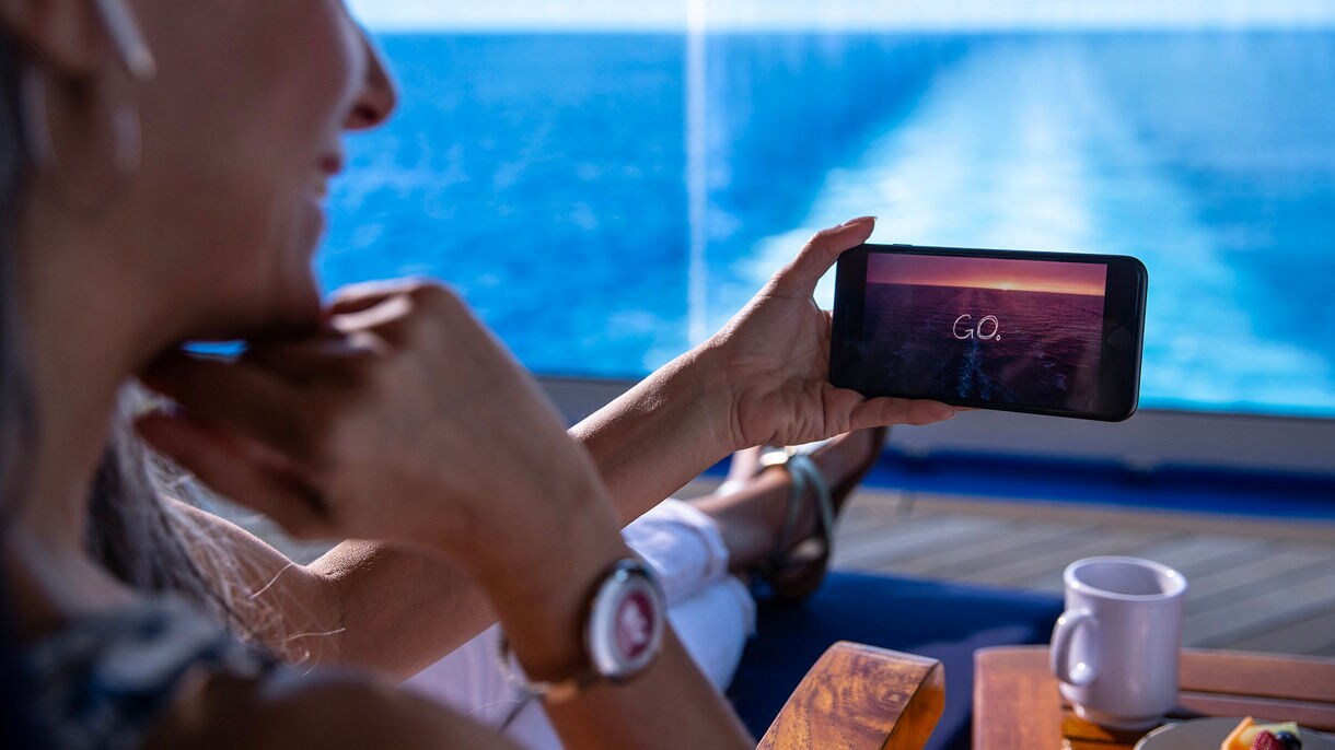 A woman watching OceanView shows in their stateroom.