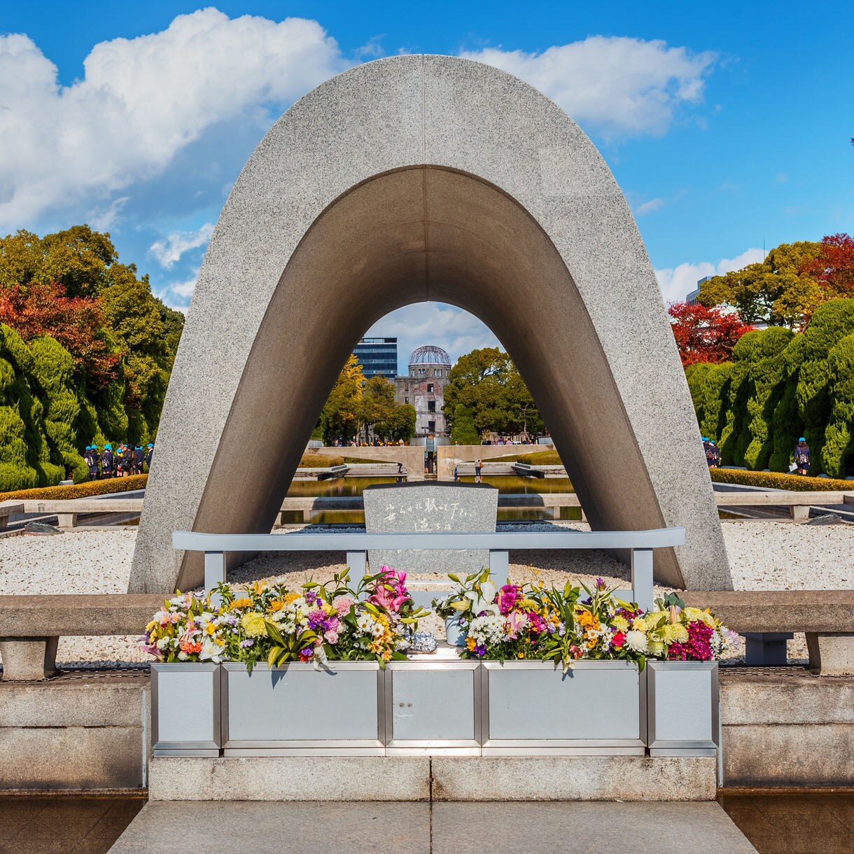 The Cenotaph for the A-bomb Victims in Hiroshima Peace Memorial Park, framed by colorful flower offerings