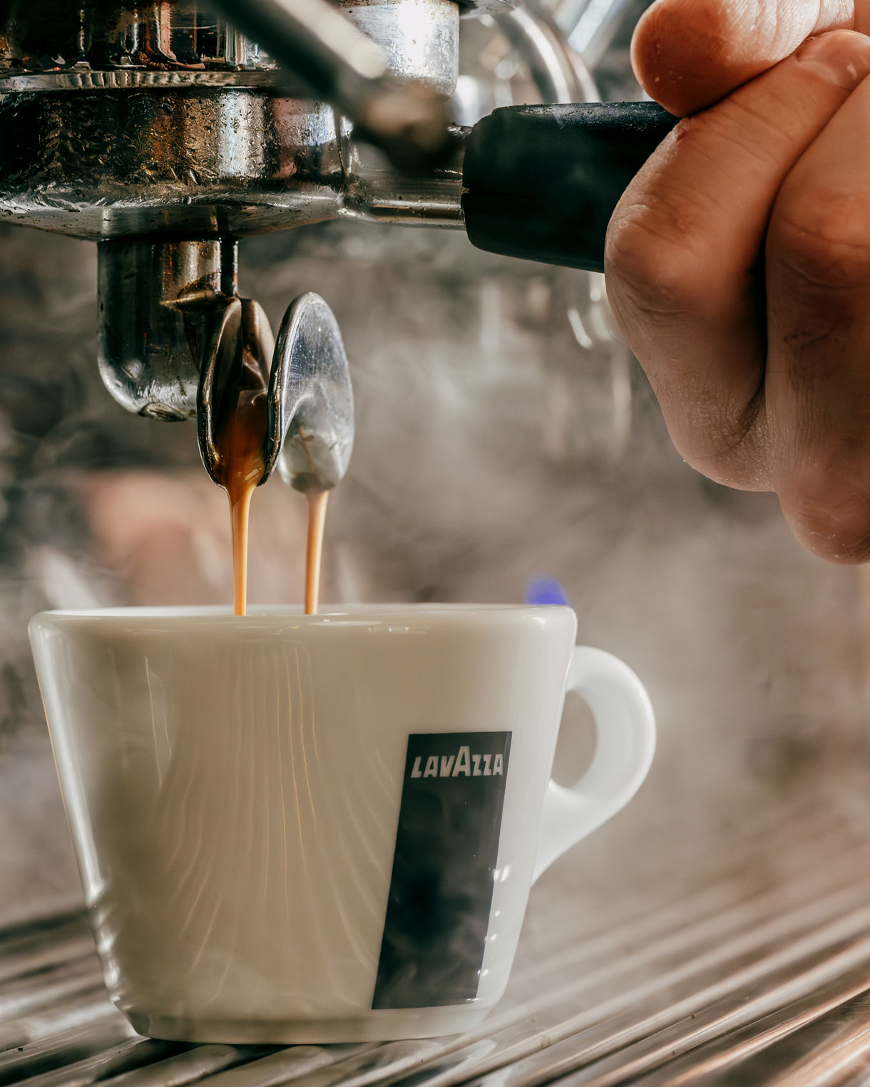 Close-up of espresso being pulled into Lavazza cup with steam.
