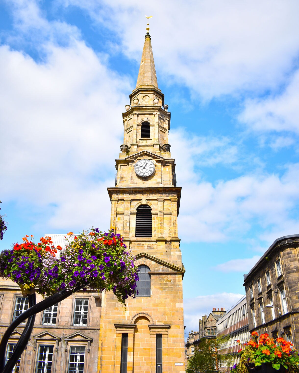 View of St Andrew’s Cathedral framed by trees with the River Ness in the foreground and forested hills in the background.