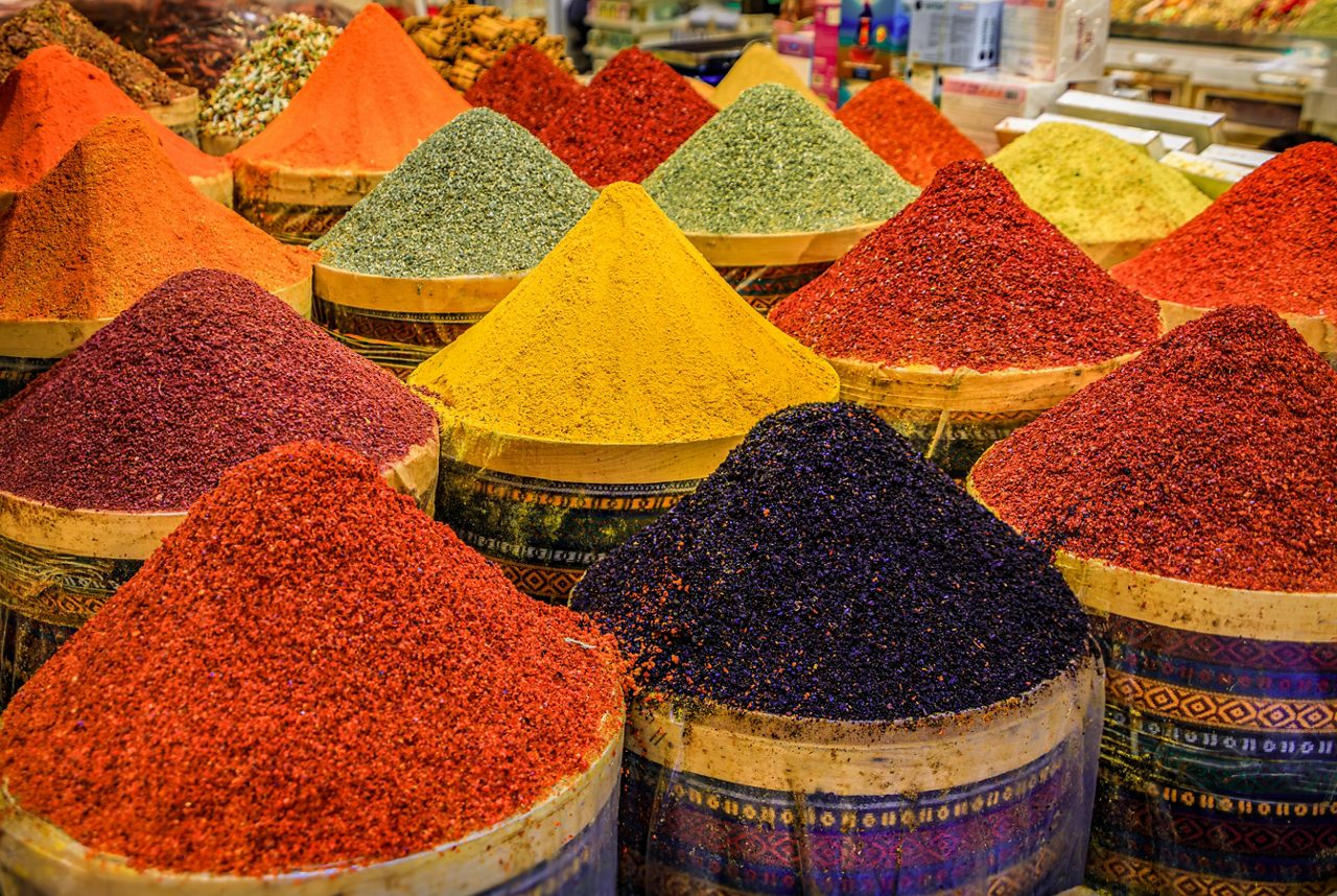 Conical piles of vibrant spices in shades of red, yellow, orange, green, and purple on display at Istanbul’s spice market.