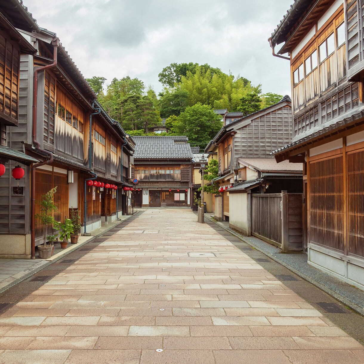 Empty stone-paved street lined with traditional wooden houses and red lanterns in Kanazawa’s historic samurai district.