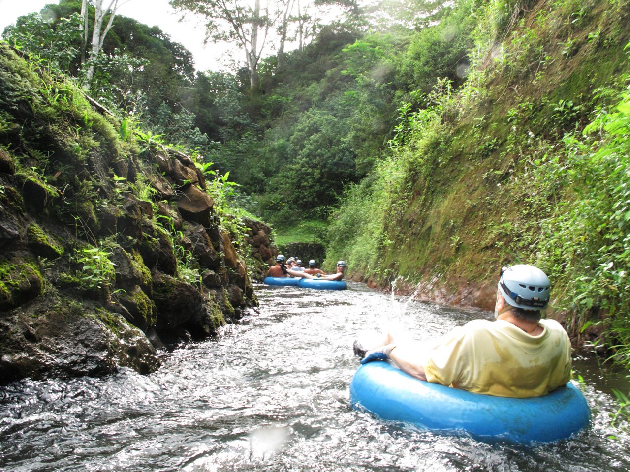 people sitting in inner tubes, floating down a river