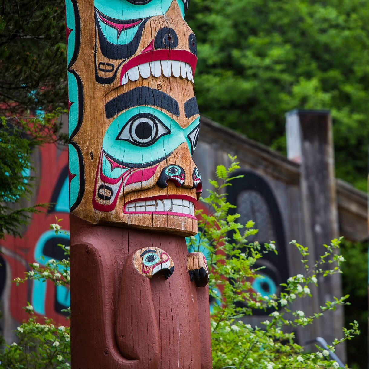 Close-up of a vibrant totem pole at Saxman Native Village, featuring intricate carvings and bright colors.