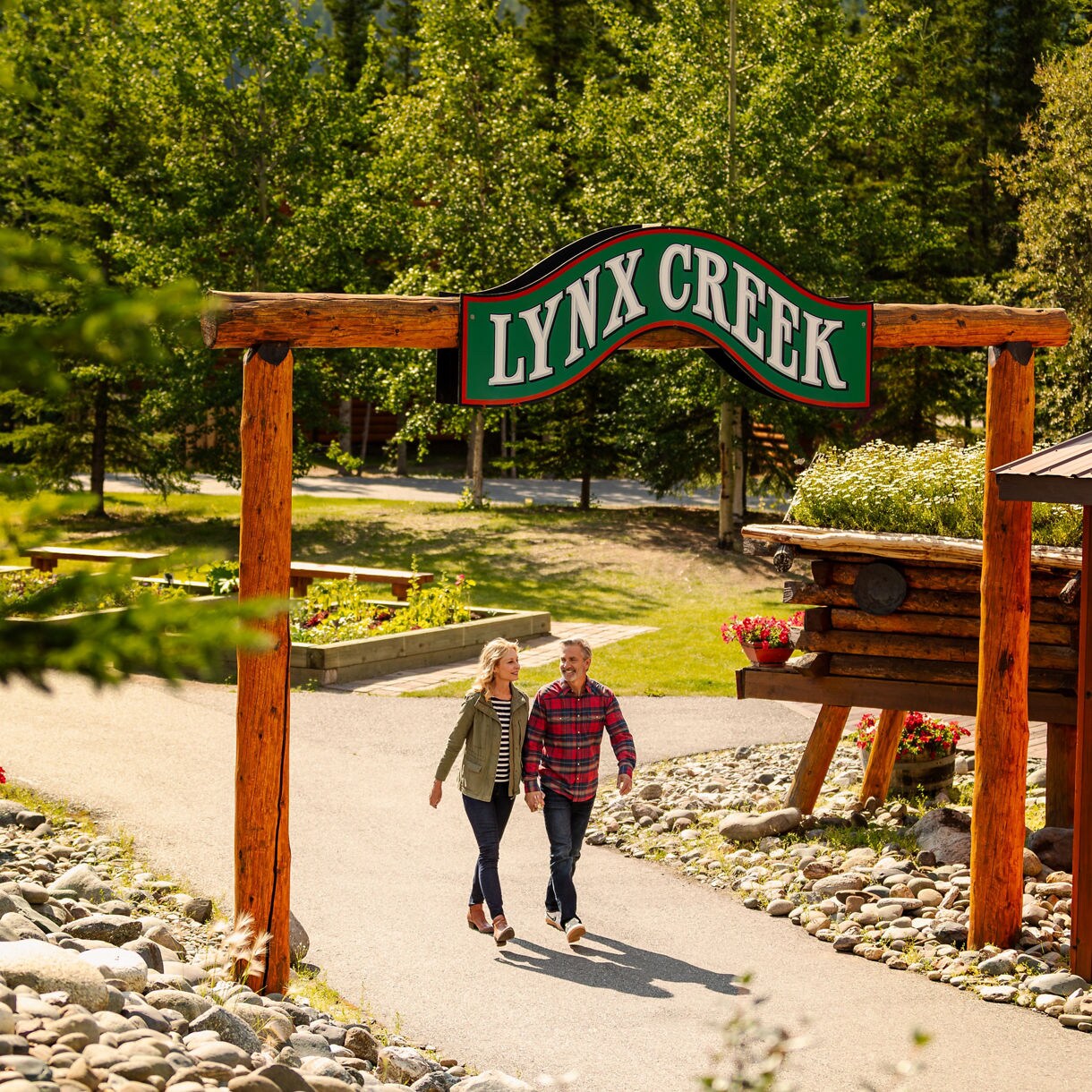 Couple walking under Lynx Creek entrance sign outdoors.