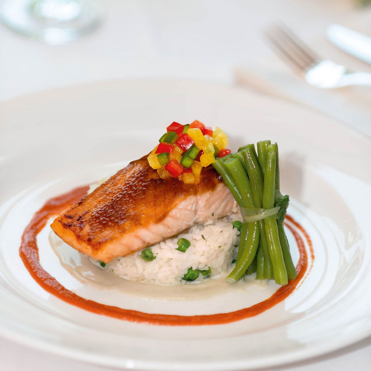 An elegant plated dish shows a white fish fillet topped with golden-brown breaded shrimp, served on creamy mushroom sauce in a white plate, with a server's hand visible.