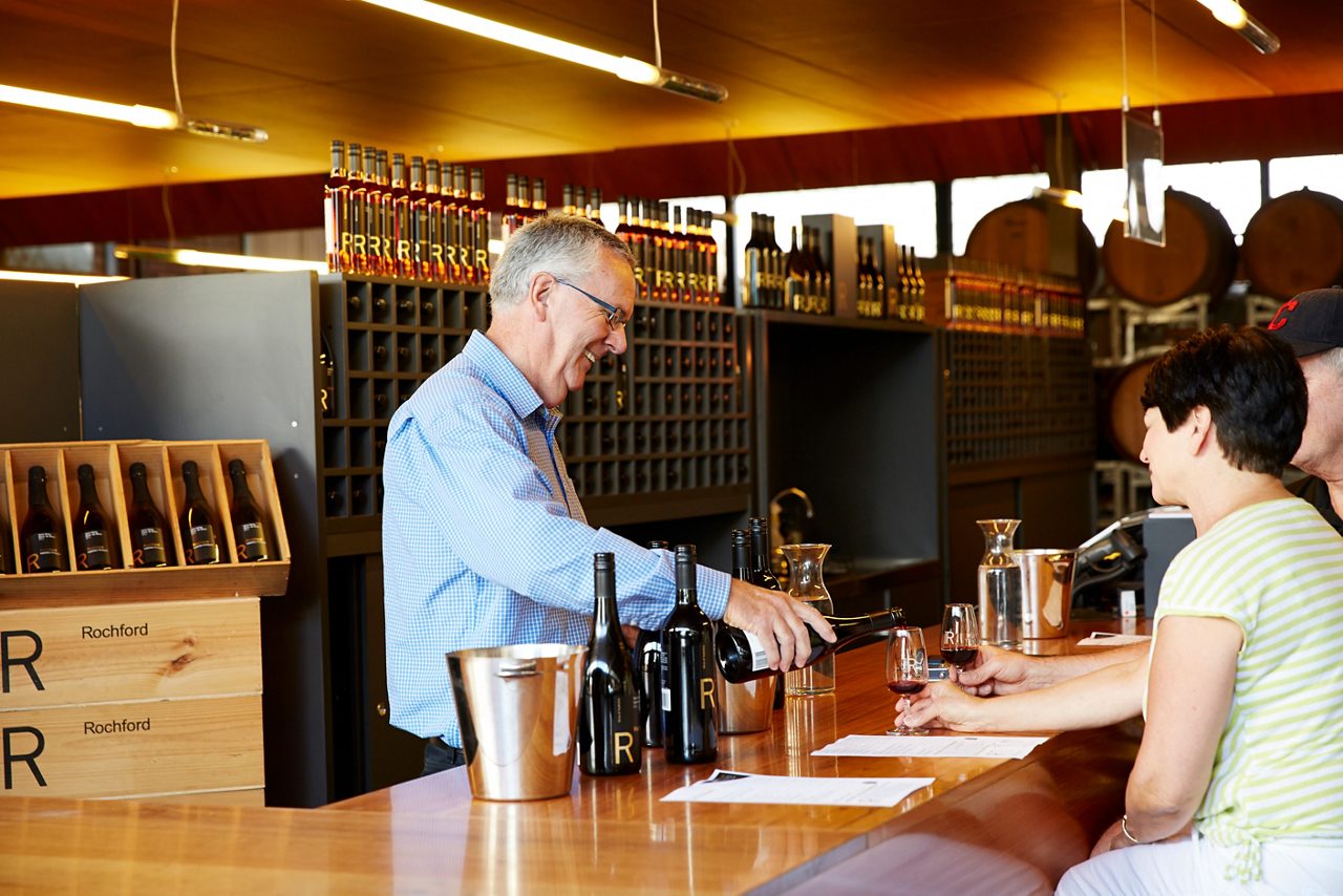 Man pouring wine at a bar, in a warm and inviting setting.