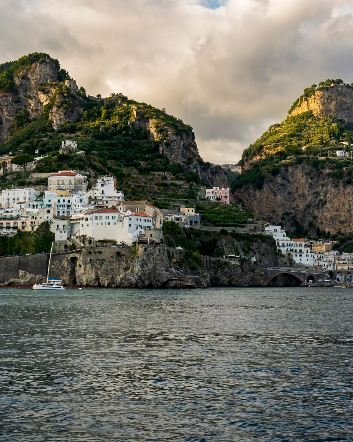 Coastal view of the Amalfi Coast with pastel-colored houses built into steep cliffs above the sea.