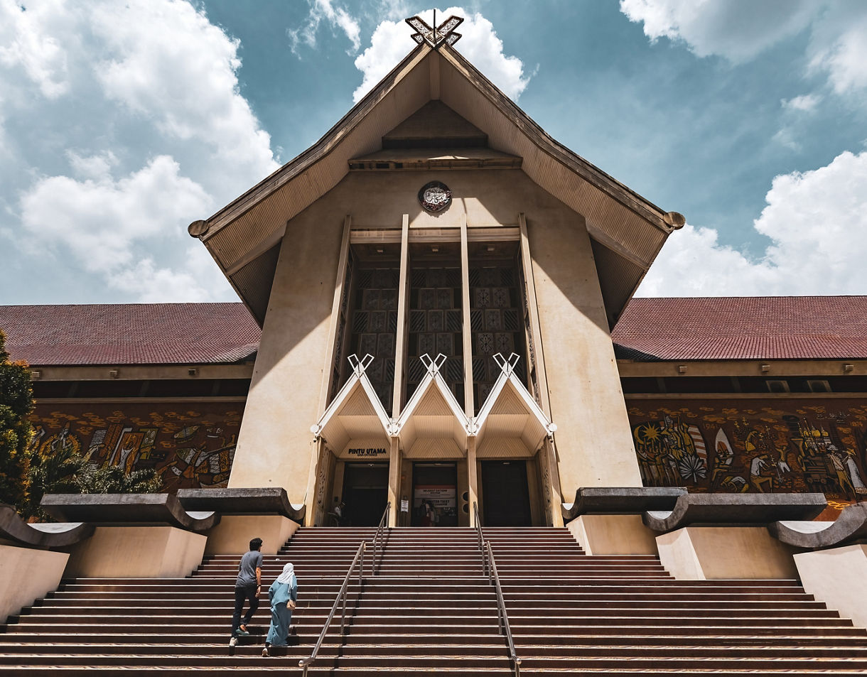Front view of Malaysia’s National Museum in Kuala Lumpur with wide steps leading to a tall gabled entrance.