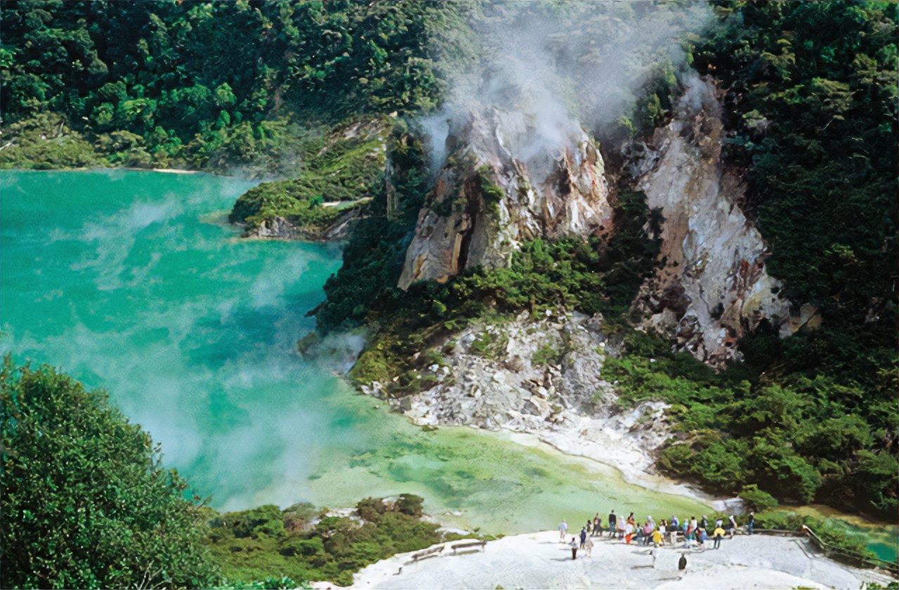 Rocky cliffside with greenery, overlooking calm turquoise water. 