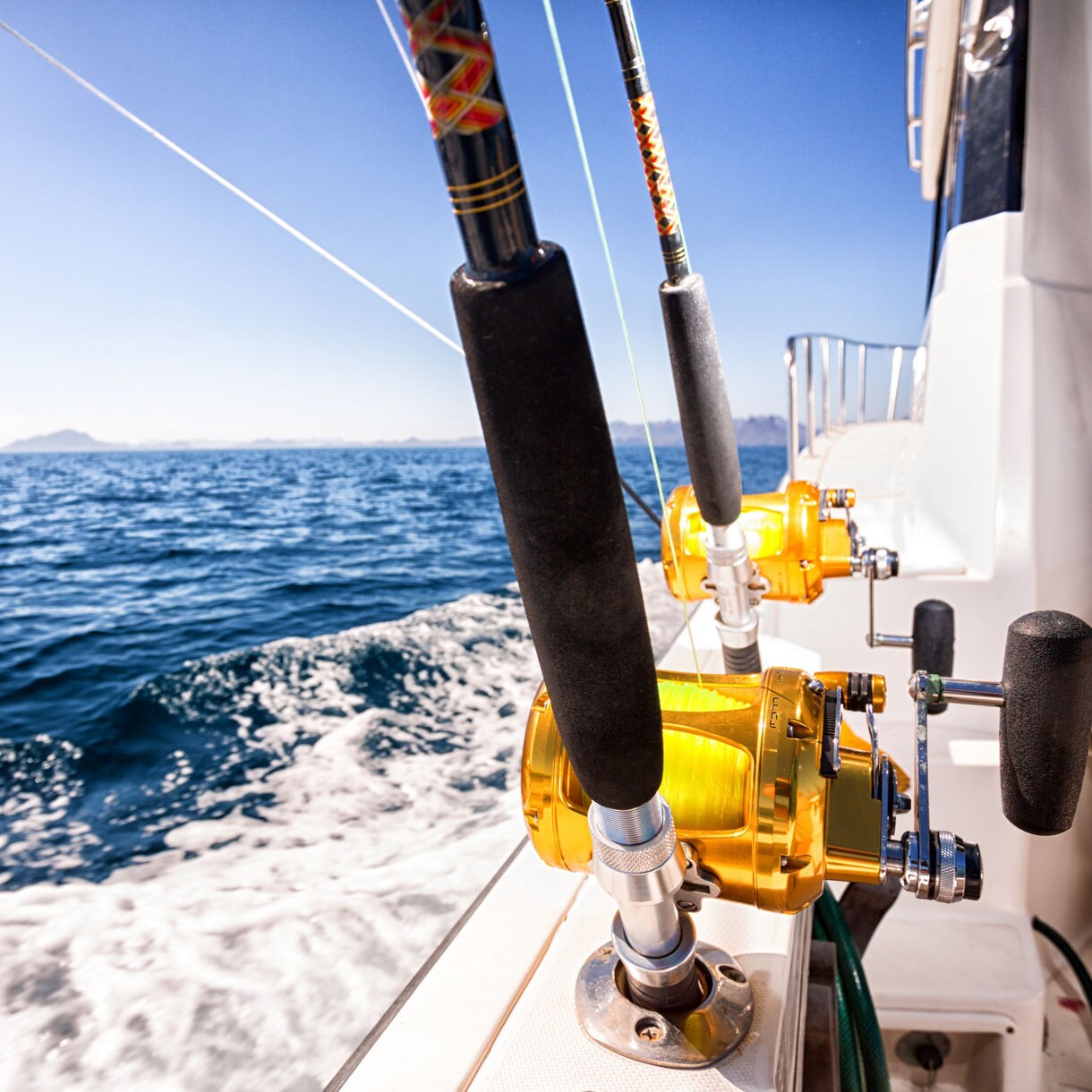 A deep-sea fishing pole stands out against the foaming waters of the ocean.