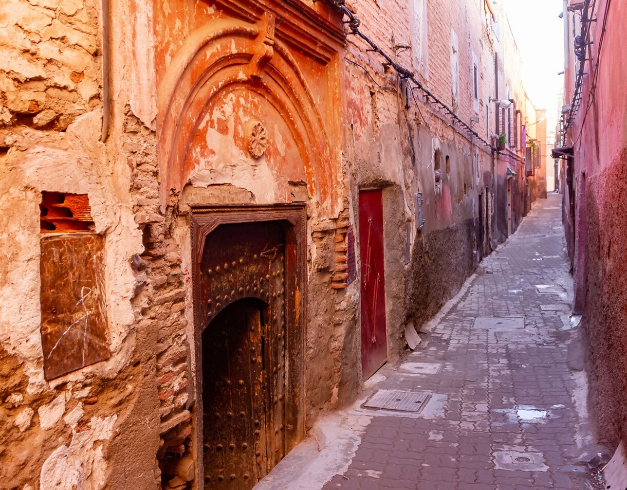 Narrow alley lined with aged, textured walls and weathered doors in warm earthy tones.