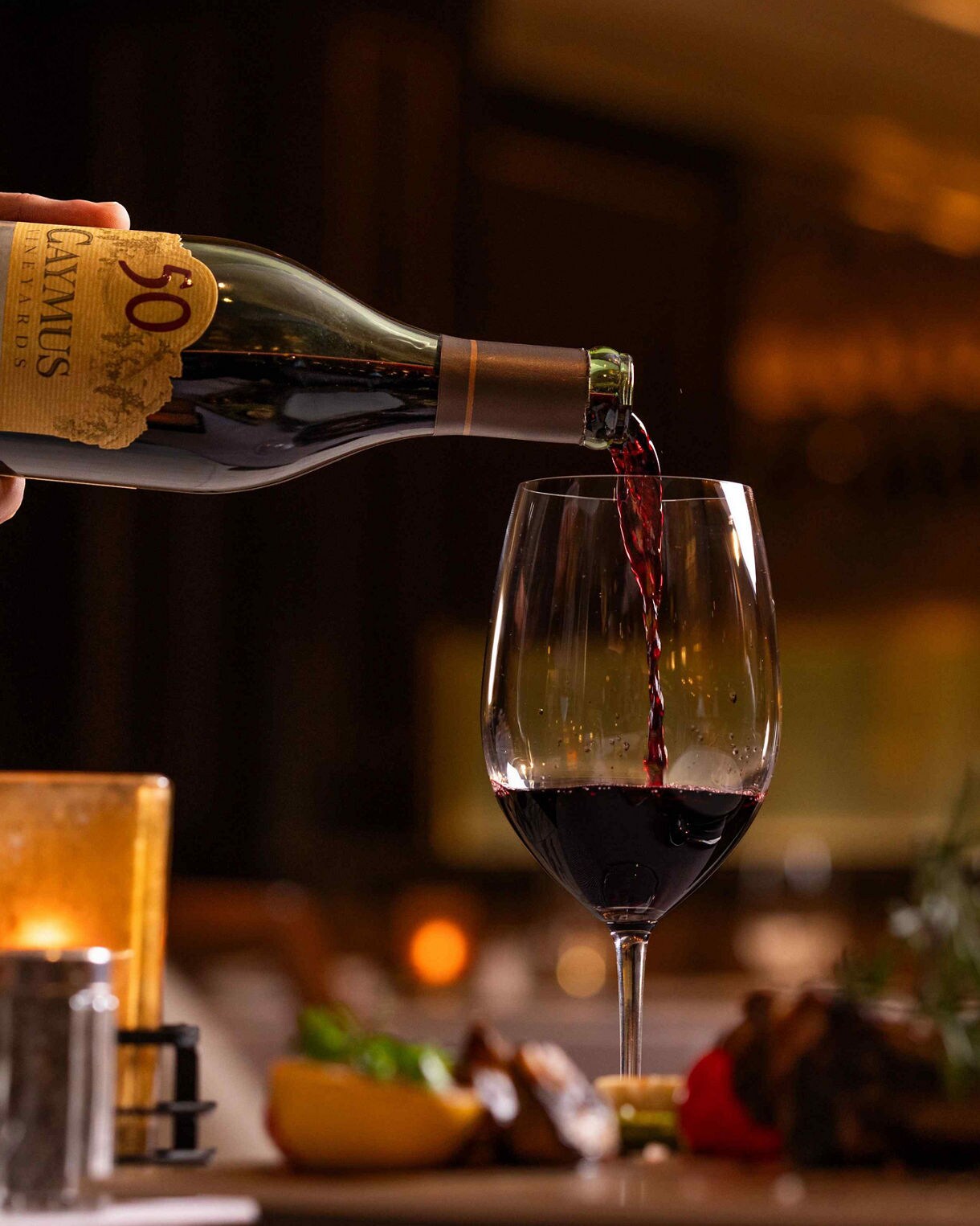 Elegant table setting with Caymus wine bottles and fine dining presentation. 