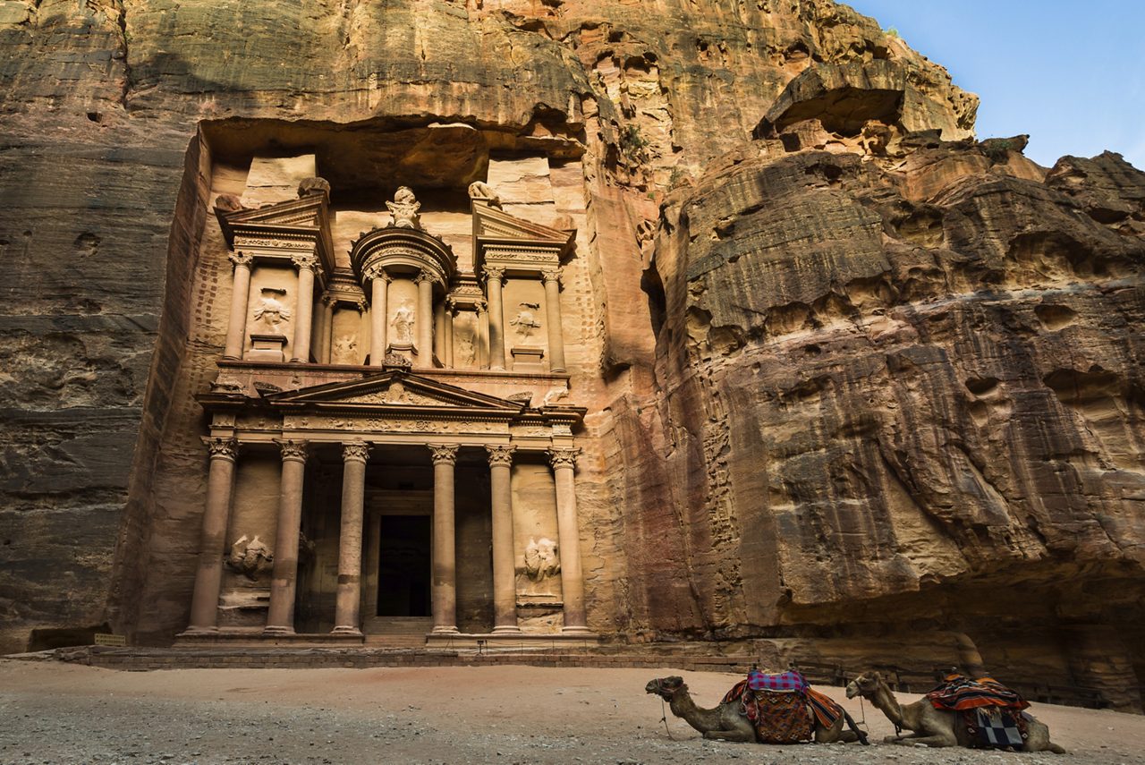 View of the ancient city of Petra in Jordan, featuring the iconic rock-cut architecture of the Treasury, with its intricate facade carved into the rose-red sandstone cliffs.