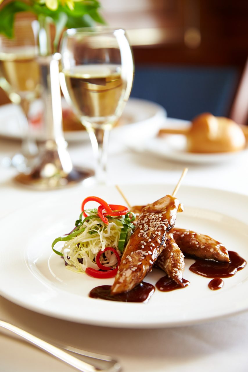 Polynesian-inspired appetizer platter with chicken and wine.