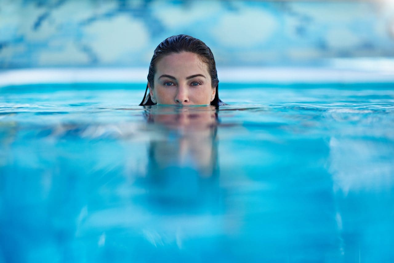 Woman in the pool, half face under the water close up.