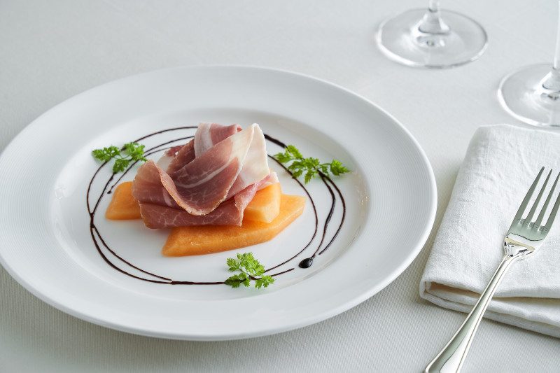 Prosciutto and melon appetizer with balsamic reduction.