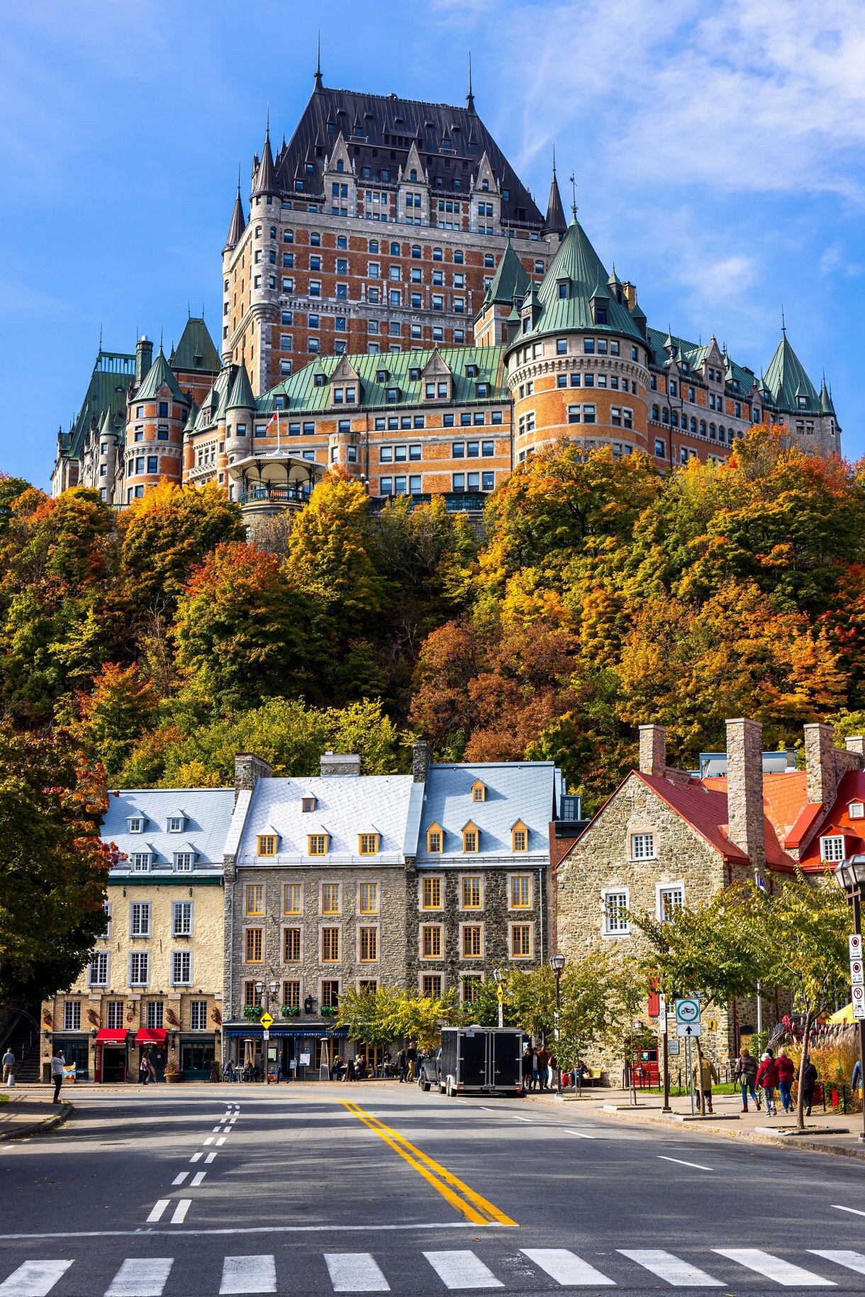 Château Frontenac on a hillside with historic stone houses and autumn foliage below.
