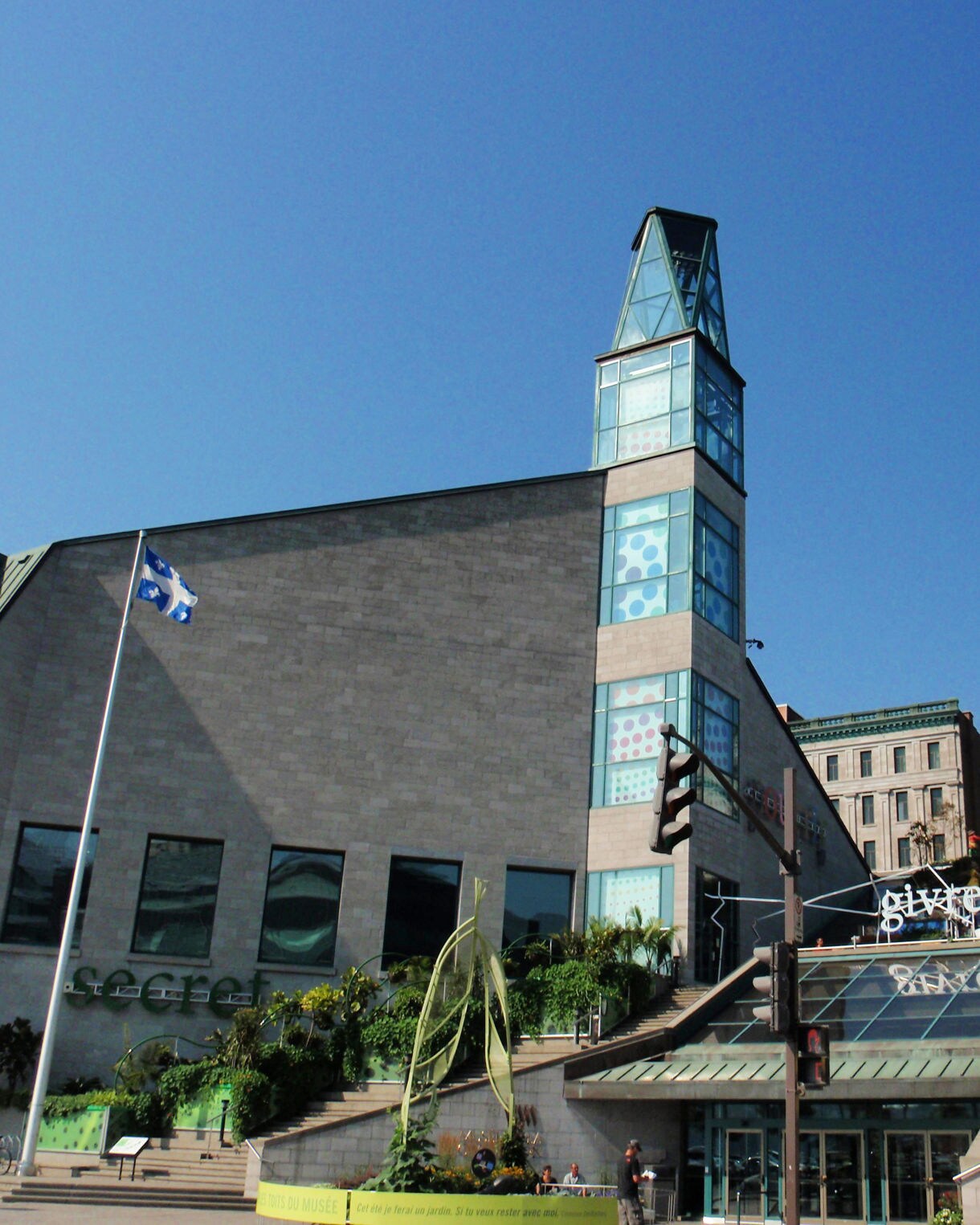 Modern glass and stone façade of the Musée de la Civilisation in Québec City with outdoor steps and displays.