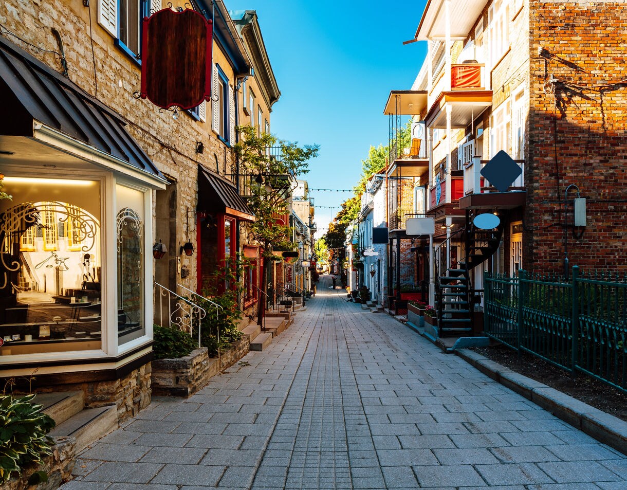 Narrow pedestrian street in Old Québec with stone buildings, boutiques and outdoor staircases.