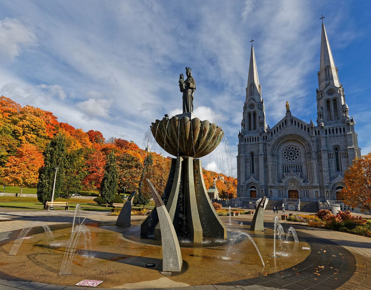 Twin-spired Sainte-Anne-de-Beaupré Basilica with fountain in foreground and fall foliage behind.