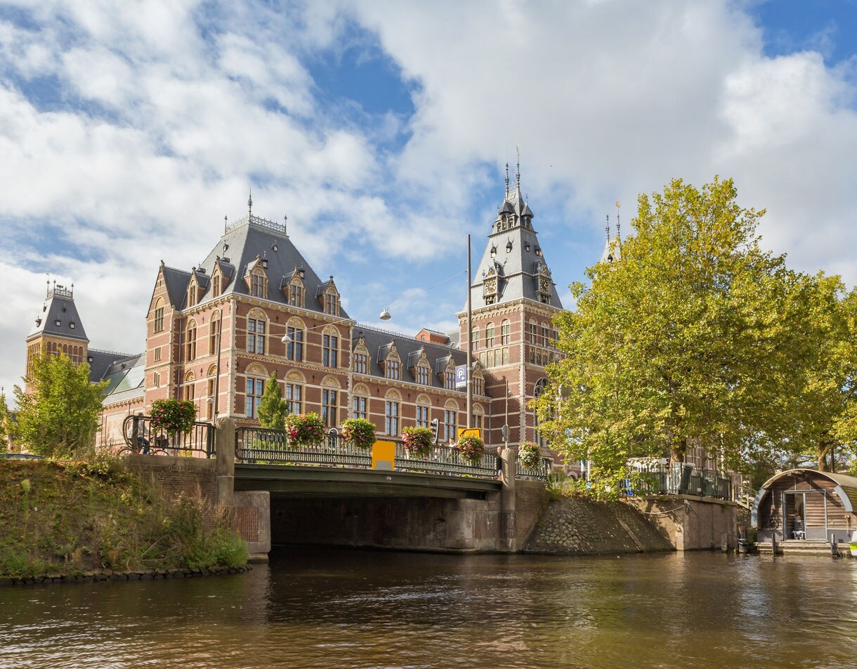 View of the Rijksmuseum in Amsterdam with its ornate brick towers and a bridge over the canal.