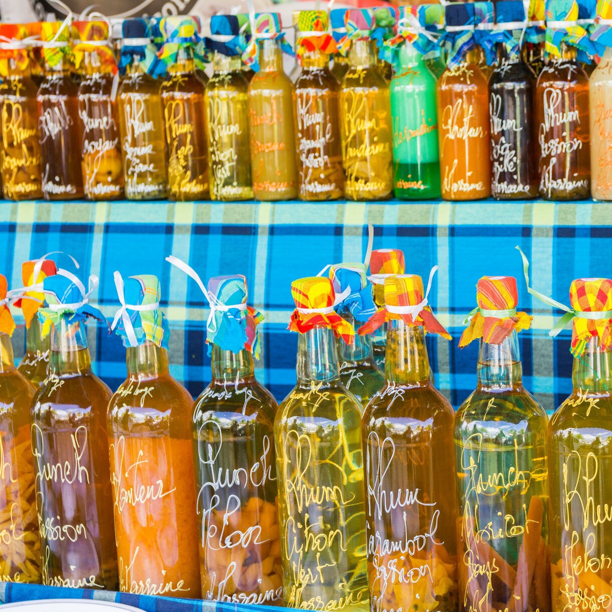 Colorful bottles of local rum and fruit liqueurs displayed on shelves at a Guadeloupe market