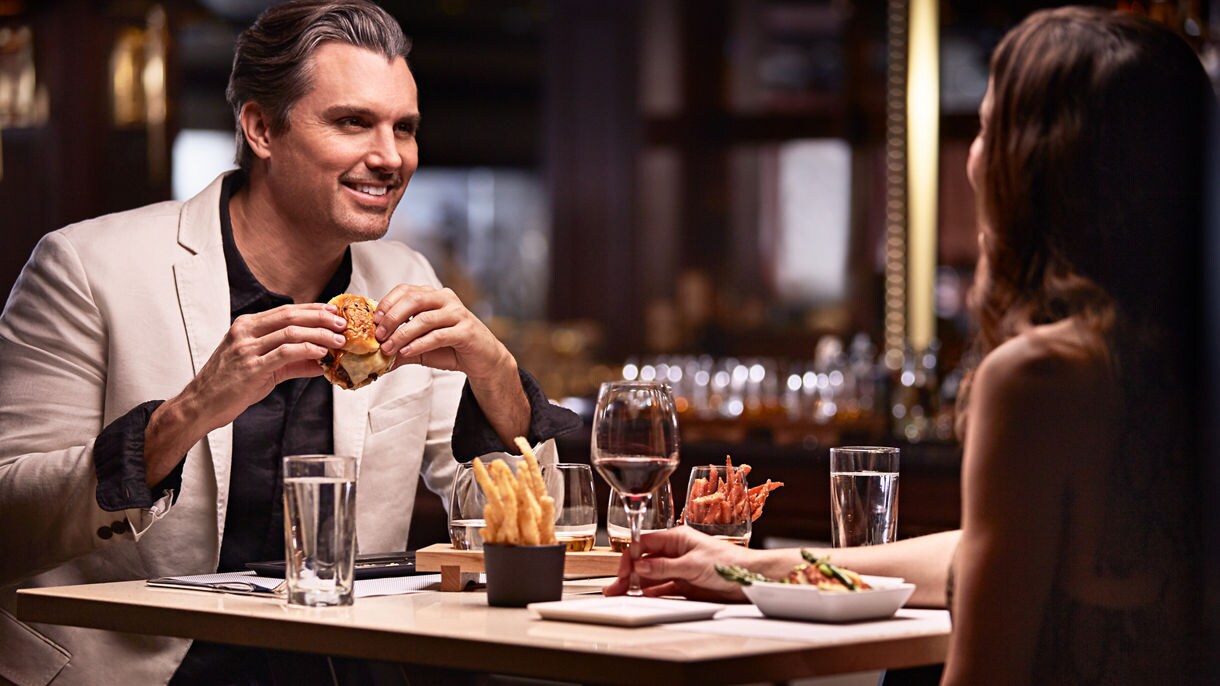 https://assets.princess.com/is/image/princesscruises/salty-dog-ruby-princess-couple-dining-burger:16x9?ts=1697266749524