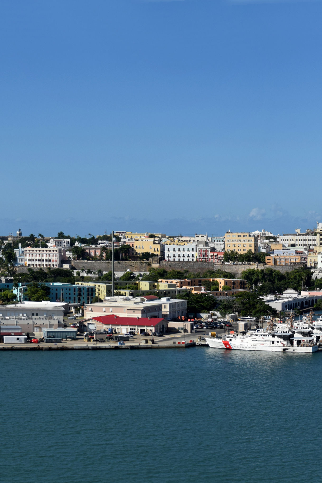 San Juan harbor with white Coast Guard vessel docked among colorful buildings and urban waterfront development