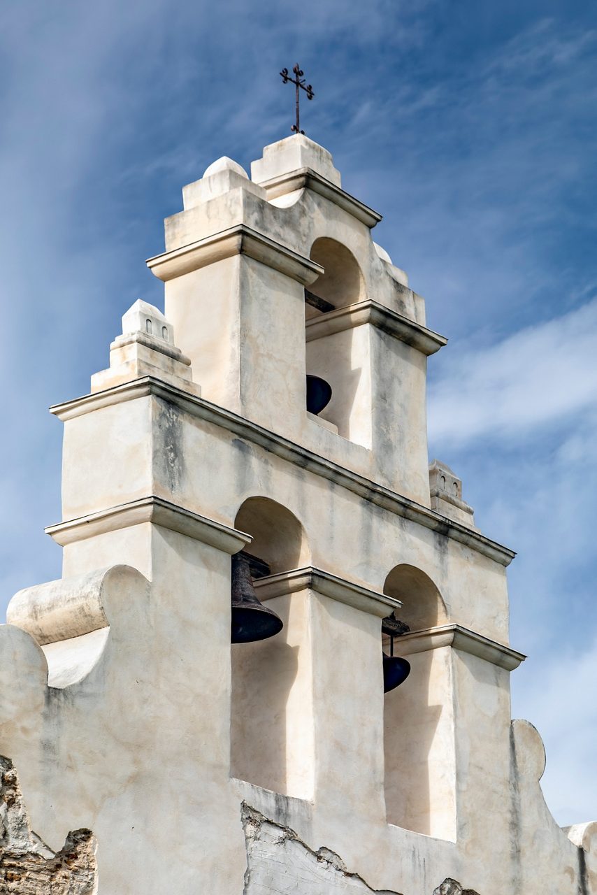 The timeless Mission San Juan Capistrano, with its intricate bell tower, standing against a clear blue sky.