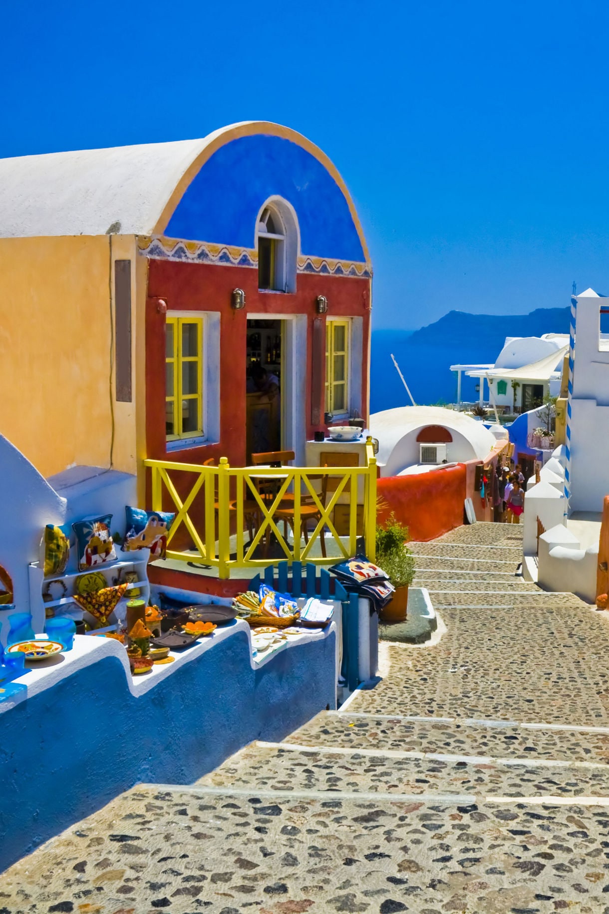 View of Oia in Santorini, Greece, featuring brightly colored buildings with blue domes and white walls, perched on a cliff overlooking the Aegean Sea.