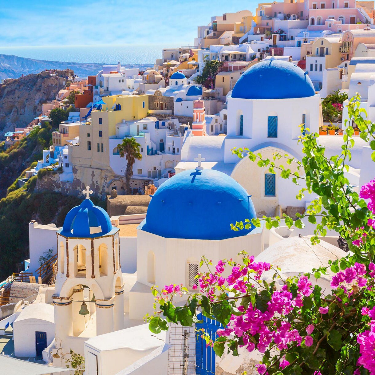 Santorini's blue-domed churches with vibrant pink bougainvillea and stunning sea views.