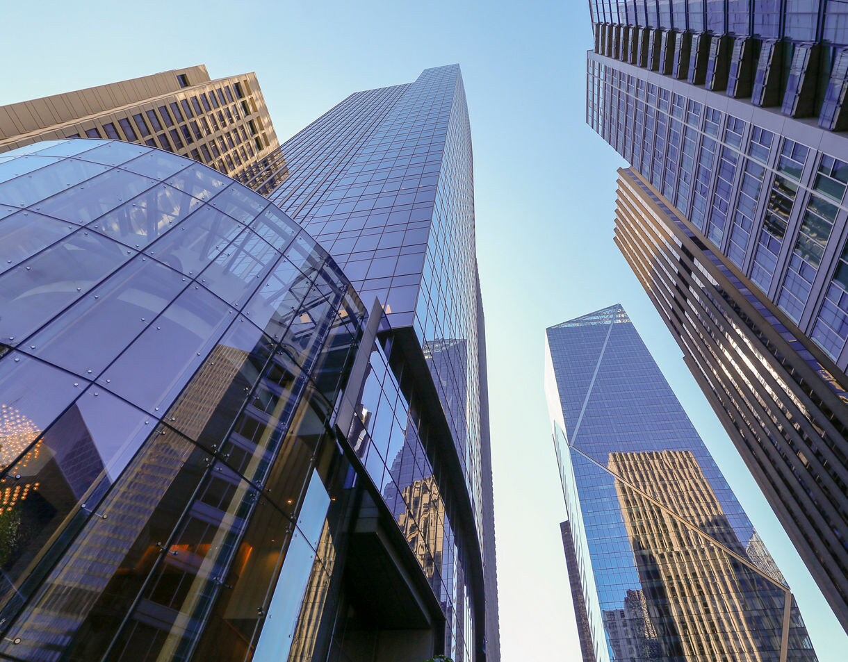 Upward view of modern glass skyscrapers in downtown Seattle against a clear blue sky.
