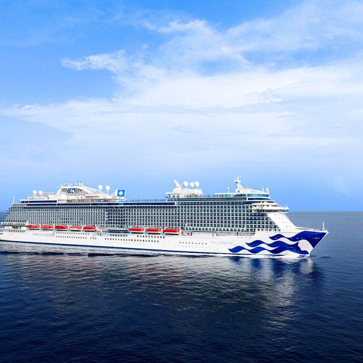 The image shows a brightly lit cruise ship captured from above as it moves through dark waters at night. Vivid blue and white waves trail behind the vessel, creating a striking visual contrast. The ship's deck is illuminated with warm lights, and a swimming pool is visible at the center. The overall scene conveys a sense of luxury, travel, and nighttime adventure.