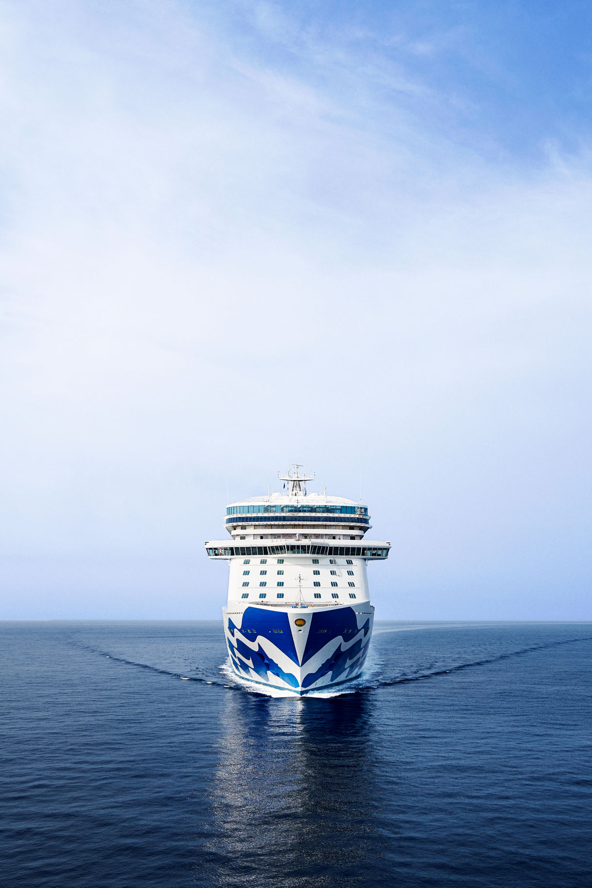 The Sky Princess ship sailing across calm blue waters under a vast, open sky, showcasing the vessel's elegant and iconic design as it moves gracefully through the ocean.