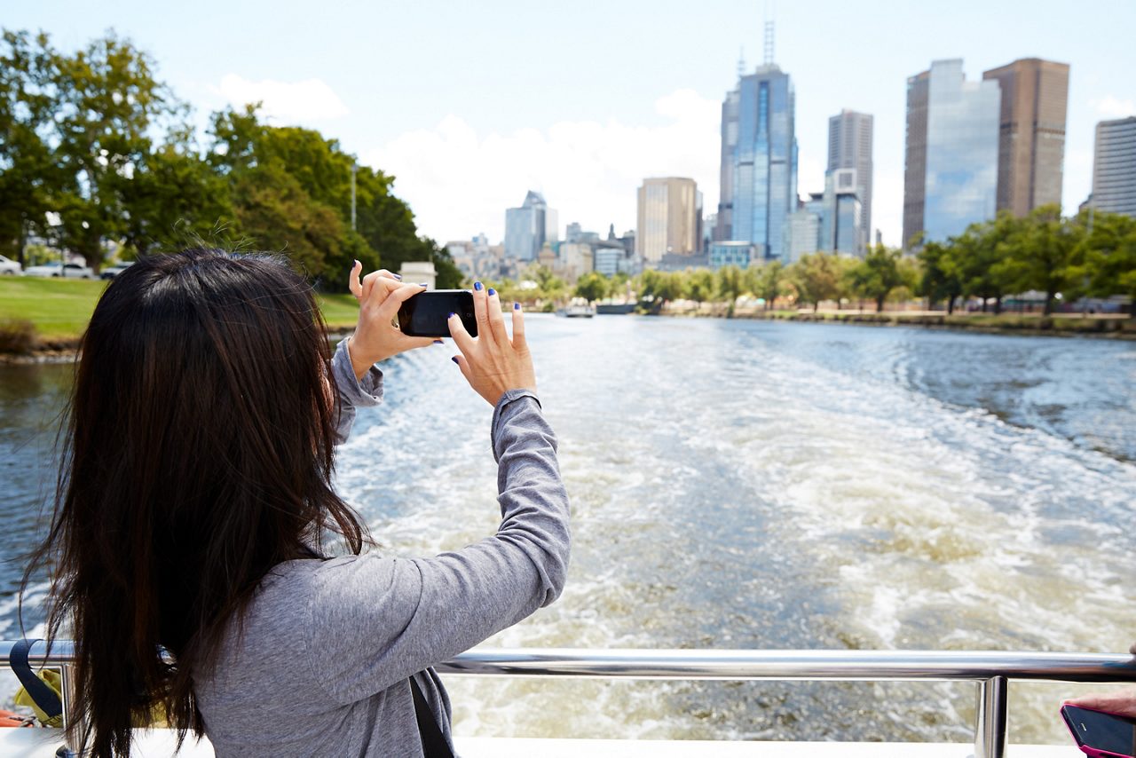  Woman takes a photo of a city skyline from a boat.