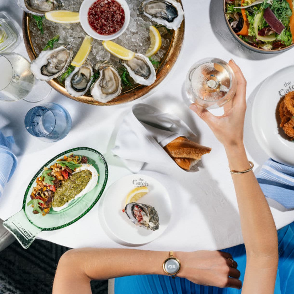 Overhead view of table with fresh oysters, seafood dishes and wine glasses.