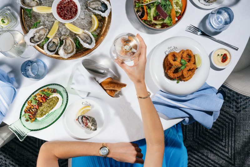 Overhead view of table with fresh oysters, seafood dishes and wine glasses.