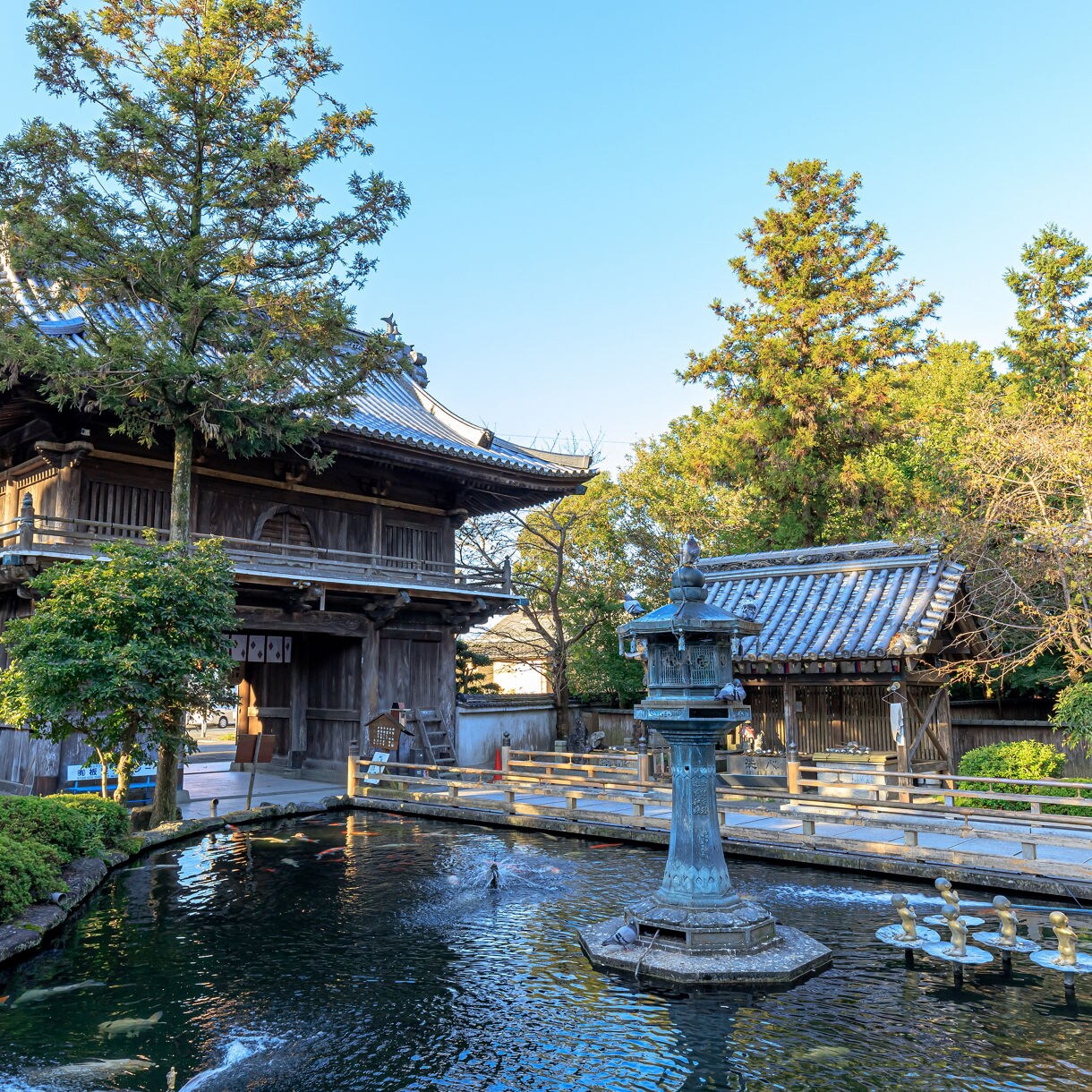 Traditional temple gate and pond with statues at Ryozen-ji in Tokushima.